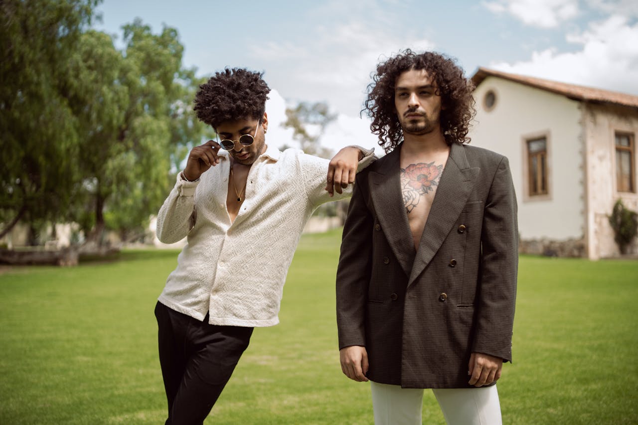 Two stylish men posing confidently outdoors in trendy outfits, exuding modern fashion vibes.